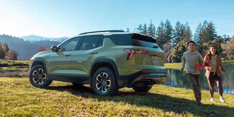 Green Chevrolet Equinox parked on grass near a lake